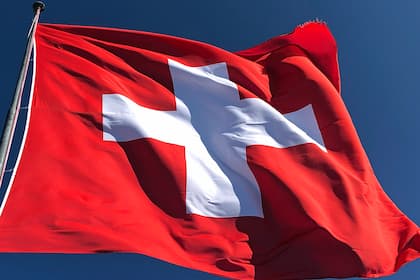 Deutsche Geschäfte nutzen Schweizer Wappen - wie kann das sein? Schweizer Flagge flattert straff im Bergwind.