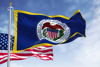 Zinsen: Eine Bank tanzt völlig aus der Reihe Die Flaggen der Notenbank Fed und der USA wehen im Wind.