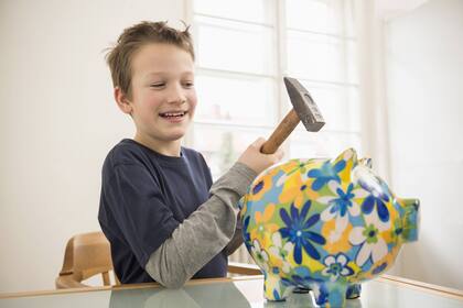 Sieben Tipps für den richtigen Umgang mit Taschengeld Ein Bub hält spasseshalber einen Hammer über sein Sparschwein (2014).