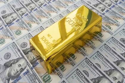 Gold: Üppigster Abfluss von Anlagegeldern seit vielen Jahren Ein Goldbarren auf einer Dollar-Noten-Oberfläche.