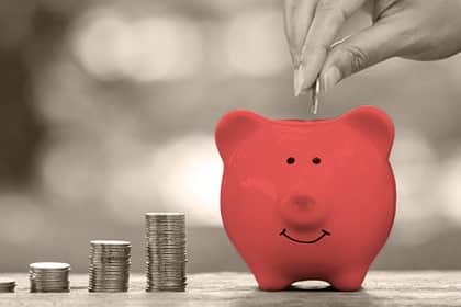 Sparpläne für Kinder: Worauf ist zu achten? Sparplan Sparschwein Münzen gestapelt einwerfen