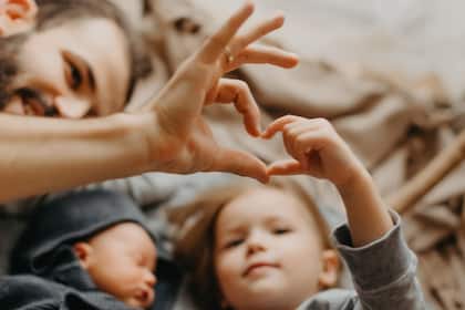 So spart man heute für die Kleinen  stylish bearded father kisses a sleeping newborn girl. Parent holding rocking child daughter son in hands. Authentic lifestyle parenting fatherhood moment. Dad family home life with 2 children