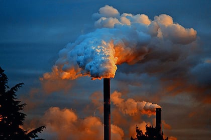 Die nachhaltige Wette: Wie sich ESG-Investments gegenüber traditionellen Indexanlagen auszahlen Industriekamine rauchen im Abendlicht.