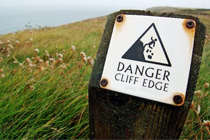 «Unser Gehirn erzählt uns ständig Geschichten»: Klassische Psycho-Stolperfallen beim Investieren - und wie sie vermieden werden Warnung für einer Klippe, wo das Gestein bröckelig ist und Abstürze möglich sind.