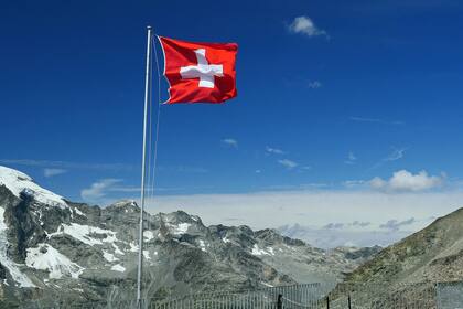 Experte: Schweizer Aktien werden von tieferen Zinsen profitieren Schweizer Flagge vor Engadiner Berglandschaft.