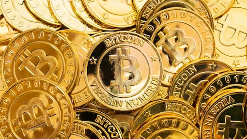 Mit Knock-Out Warrants Open End gehebelt in Bitcoin investieren Bitcoin cryptocurrency background. A bunch of golden bitcoin, Digital currency