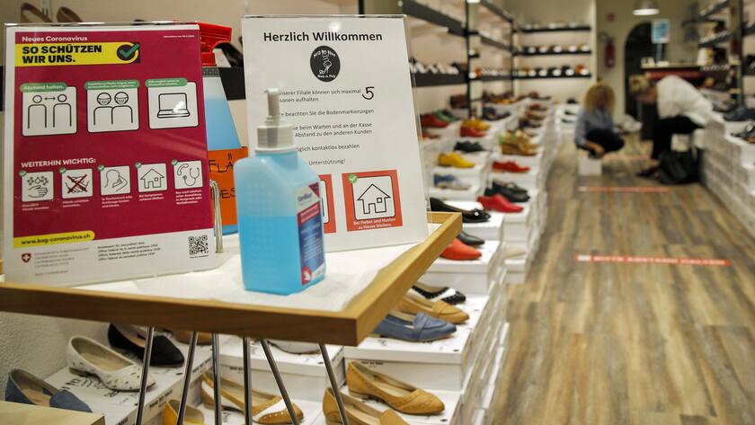 Hinweise auf Regeln, Desinfektionsmittel, Masken: Einkaufen in einem Schuhgeschäft in Zeiten der Coronakrise.