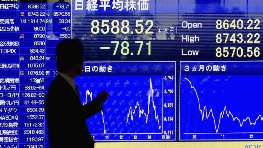 Passant beobachtet eine Anzeigetafel mit fallenden Aktienkursen an der Tokyo Stock Exchange in Tokio.