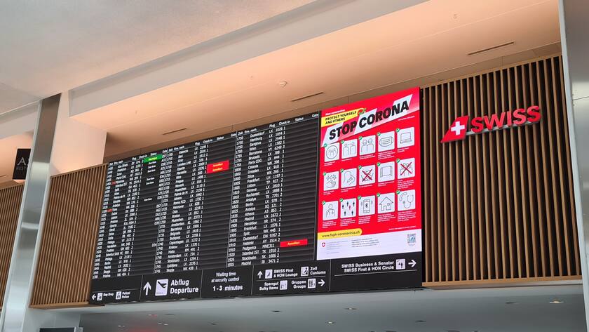 Corona ist beim Reisen allgegenwärtig: Anzeigetafel und Corona-Warnhinweis am Flughafen Zürich.