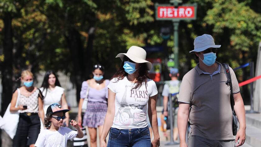 Touristen in Paris in tragen bei einer Metro-Station Gesichtsmasken.