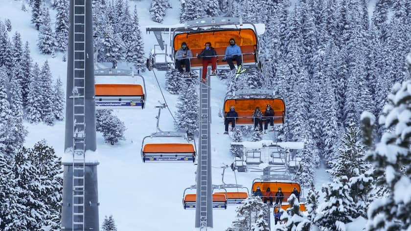 Skitouristen mit Gesichtschutz auf einem Sessellift in Grindelwald.