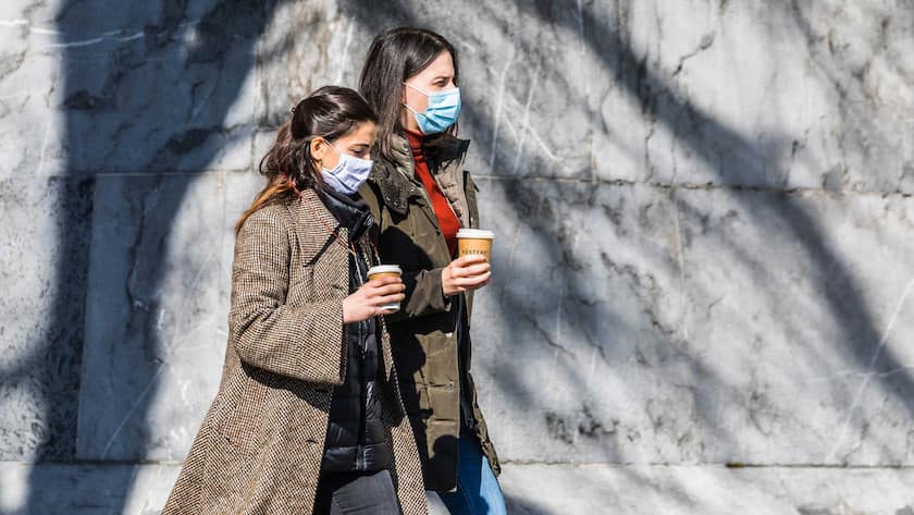 Zwei Frauen laufen in Bern mit einem Kaffee in Richtung Bundesterasse.