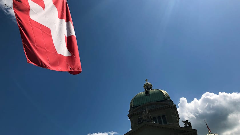 Schweizer Flagge gegenüber der Kuppel des Bundeshauses in Bern.