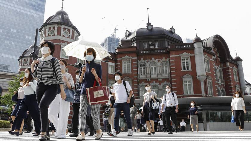 Menschen am Hauptbahnhof von Tokio, die wegen der Pandemie nach wie vor Masken tragen müssen.