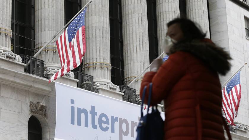 Eine Fussgängerin mit Atemschutzmaske vor dem Gebäude der New Yorker Stock Exchange.