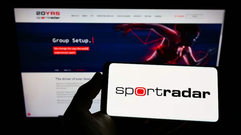 Person haltend smartphone mit Schriftzug des Sportarten Daten Gesellschaft Sportradar.