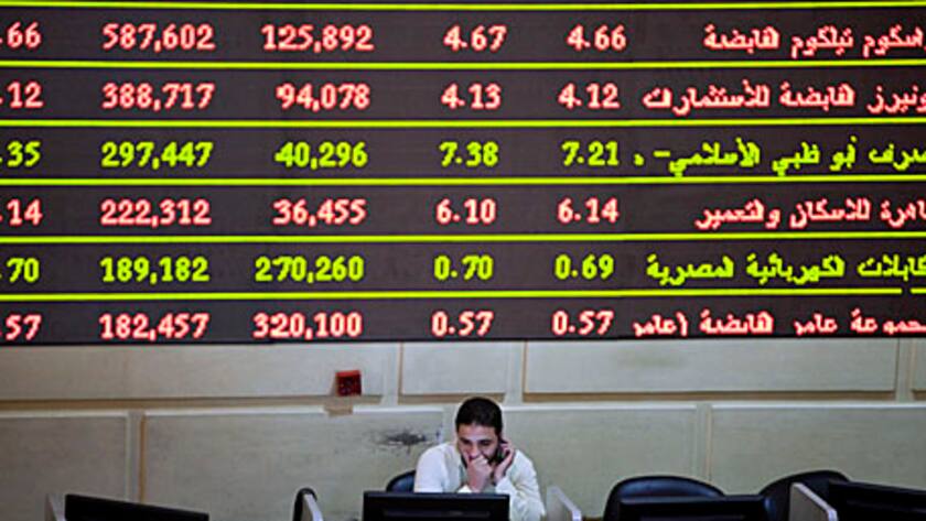 A trader works beneath an electronic screen showing stock prices at the Egyptian stock exchange in Cairo, Egypt, on Tuesday, April 23, 2013.