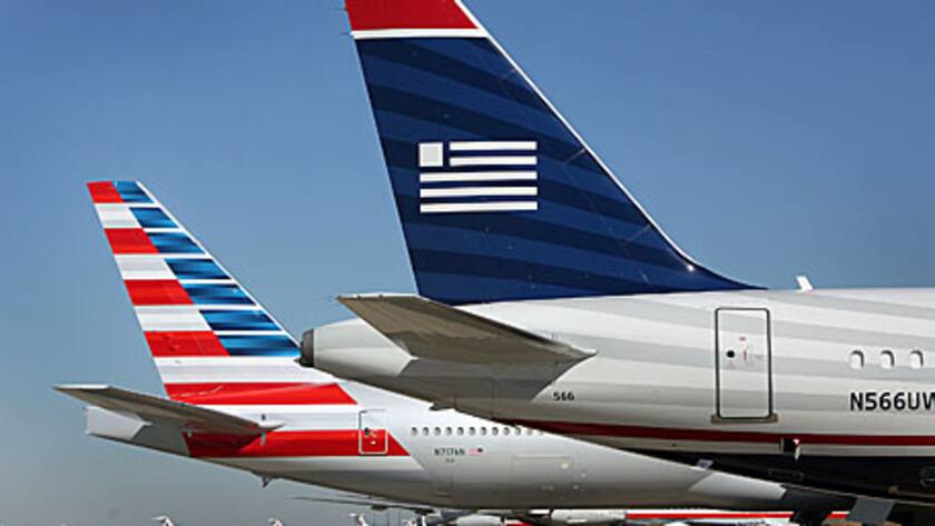 An AMR Corp.'s American Airlines airplane, left, and a US Airways Group Inc. airplane sit parked at a gate at Dallas Fort Worth Airport in Fort Worth, Texas, U.S., on Thursday, Feb. 14, 2013.