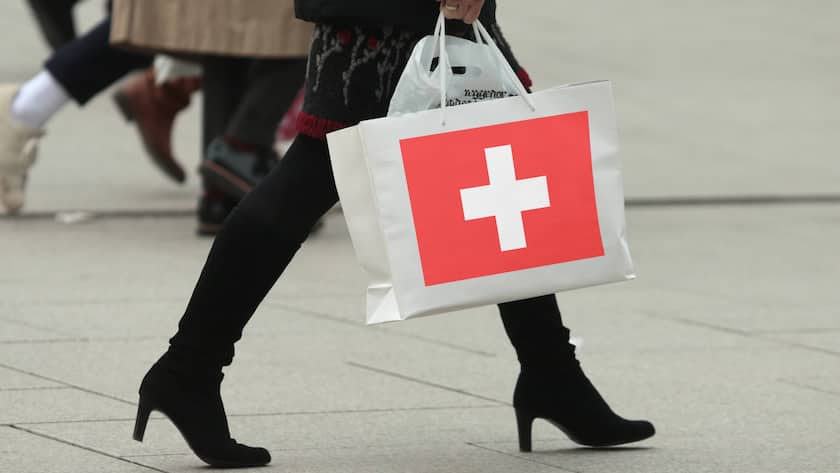 Eine Frau mit Stiefeln trägt eine Tragetasche mit Flagge der Schweiz.