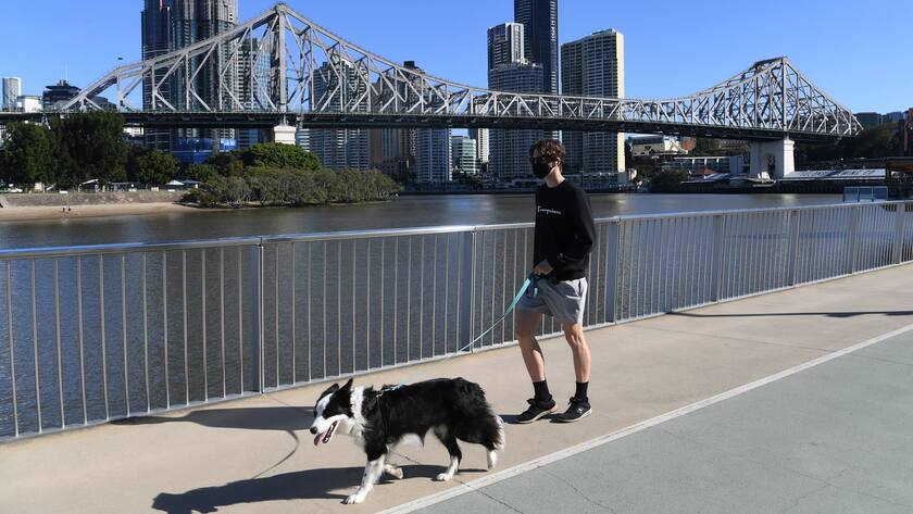 Lockdown in Australien: Ein Mann mit Gesichtsmaske spaziert mit einem Hund.