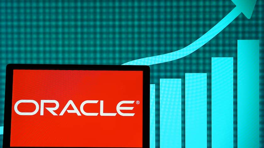 Das Logo von Oracle auf einem Bildschirm mit dem Aktienkurs im Hintergrund.