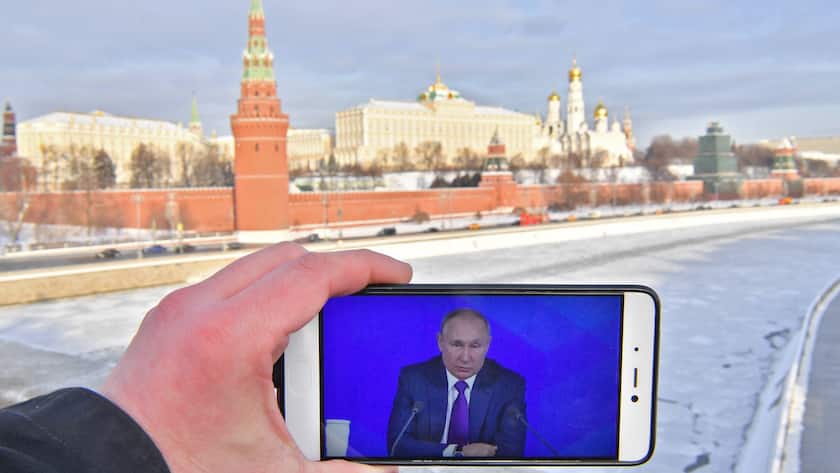 Der russische Präsident Wladimir Putin auf einem Smartphone an der Bolschoi-Kamenny-Brücke, mit dem Moskauer Kreml im Hintergrund.