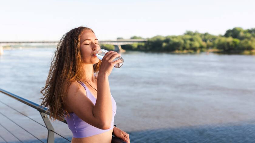 Eine Frau greift während des Sports zur Wasserflasche.