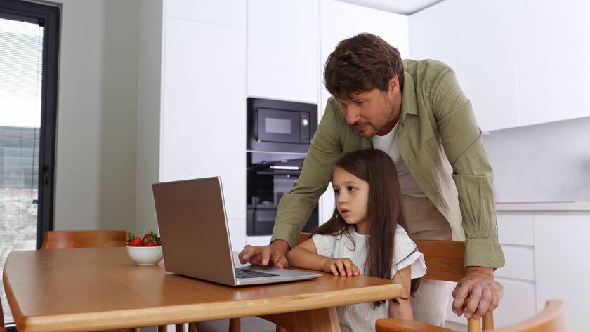 Vater hilft einem Mädchen bei der Benutzung eines Laptops zu Hause.