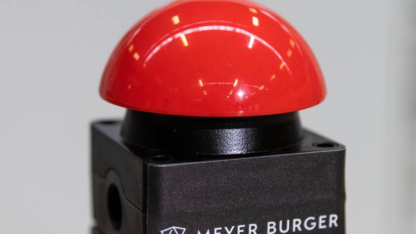 Ein roter Knopf mit dem Logo von Meyer Burger.