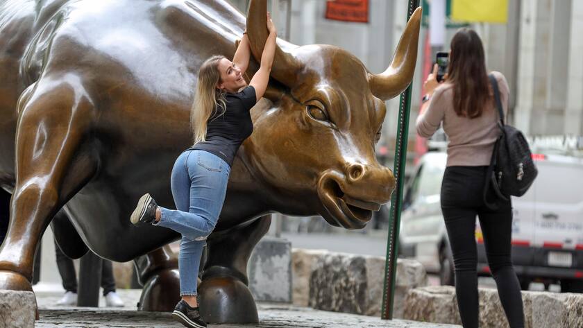 Touristin lässt sich in der Nähe der New York Stock Exchange mit dem Börsenbullen fotografieren.