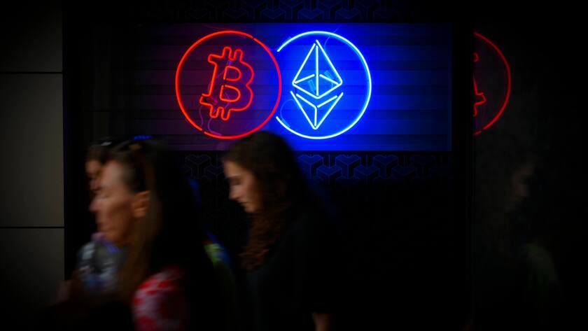 Fussgängerinnen vor einer Neonanzeige der Kryptowährungsbörse in Warschau, Polen.