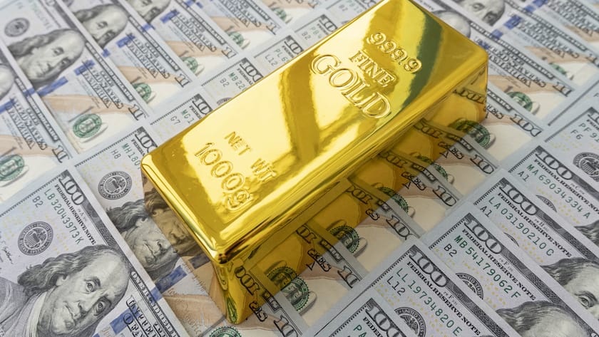 Ein Goldbarren auf einer Dollar-Noten-Oberfläche.