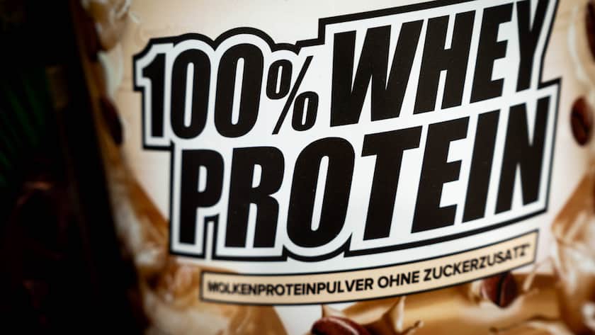 Nahaufnahme einer Proteinpulver-Verpackung mit der Aufschrift 100% Whey Protein Molkenproteinpulver ohne Zuckerzusatz.