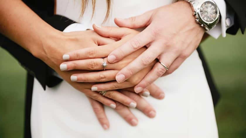 Ein Brautpaar präsentiert seine Eheringe