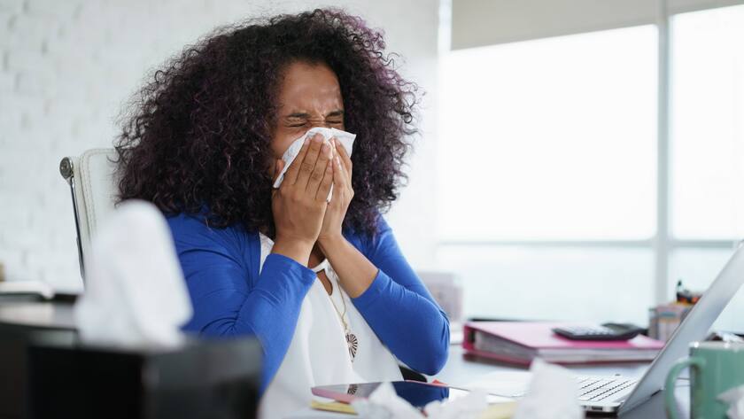 Eine erkältete Frau im Büro.