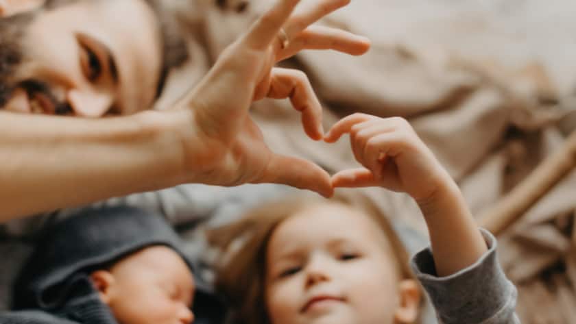 stylish bearded father kisses a sleeping newborn girl. Parent holding rocking child daughter son in hands. Authentic lifestyle parenting fatherhood moment. Dad family home life with 2 children