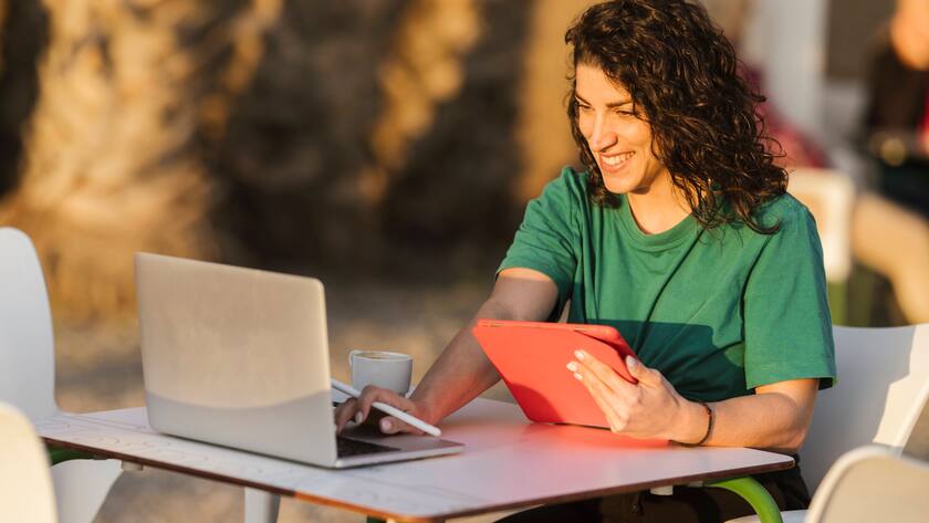 Glückliche Frau sitzt im Freien Cafe mit ihrem Laptop.