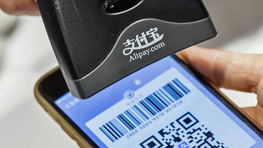 An employee scans a quick response (QR) code displayed on the Ant Financial Services Group's Alipay app, an affiliate of Alibaba Group Holding Ltd., inside a store in Hong Kong, China, on Tuesday, Nov. 1, 2016.
