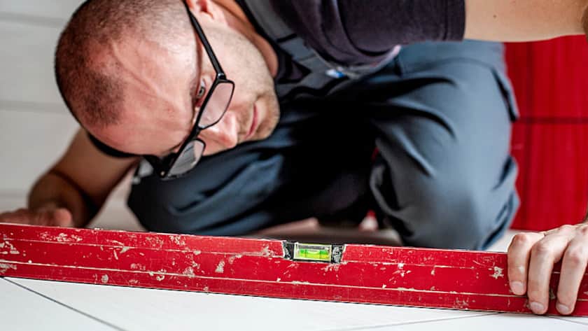 Ein Bodenleger überprüft die verlegten Platten.