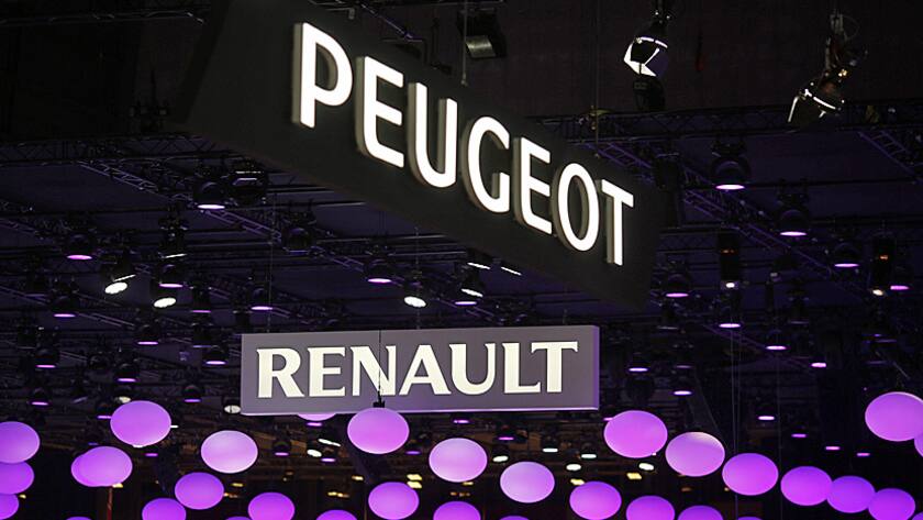 The logos of Peugeot, a unit of PSA Peugeot Citroen, and Renault sit above the Renault SA pavilion during the preview day at the Paris Motor Show in Paris, France, on Thursday, Oct. 2, 2014