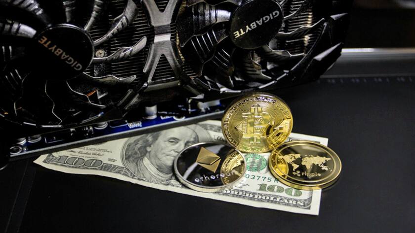 digitale und reale Welt: Ein Mining-Gerät, Münzen mit Kryptowährungs-Symbolen und eine Dollarnote.