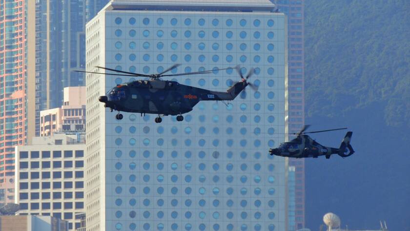 Chinesische Militärhelikopter fliegen über den Hafen von Hongkong, im Hintergrund das Gebäude des Handelskonzerns Jardine Matheson.