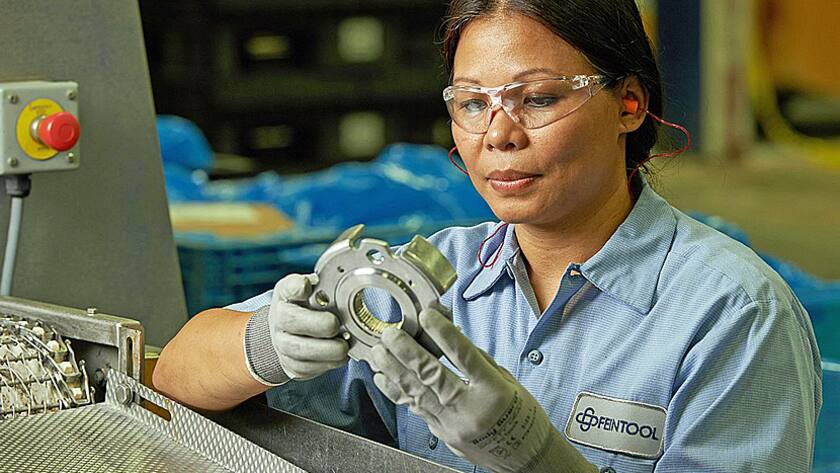 Eine Feintool-Mitarbeiterin verarbeitet Getriebeteile.