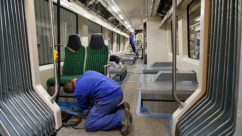 Ein Mitarbeiter bei der Sitzmontage in einem Zug von Stadler Rail.
