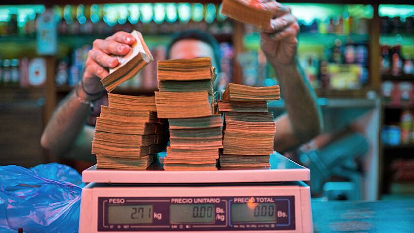 A manager weighs banknotes on a scale at a bakery in Caracas, Venezuela, on Thursday, Oct. 13, 2016.