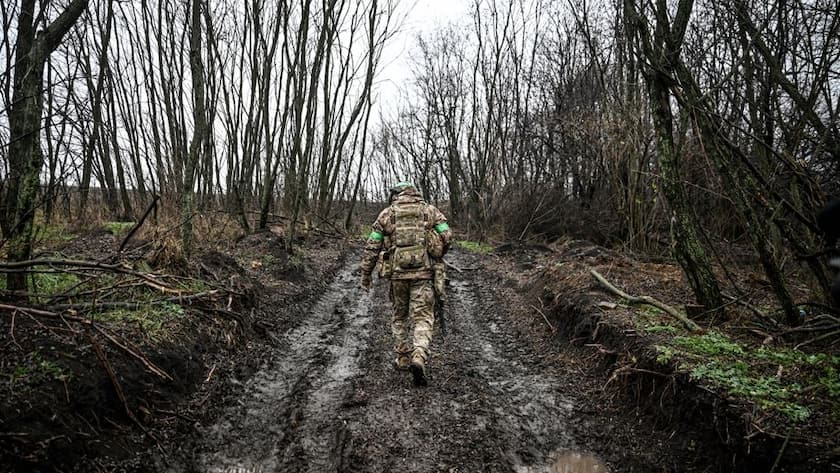 Ein Soldat marschiert während eines Kampfeinsatzes in Richtung Pokrowsk auf einer schlammigen Strasse zwischen Bäumen (Ukraine, November 2025).