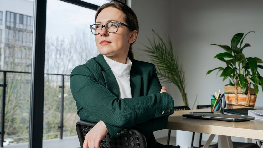 Eine Frau mit Brille schaut an ihrem Arbeitsplatz in die Ferne (