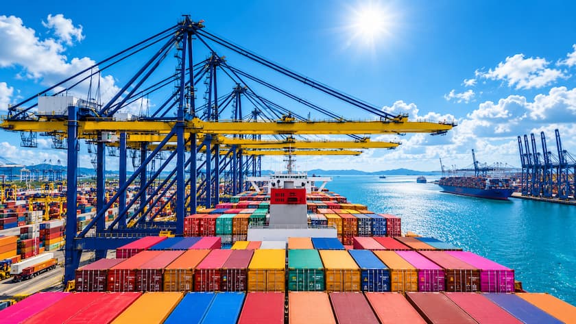 Ein Containerschiff wird in einem internationalen Hafen mithilfe grosser Hafenkräne entladen.