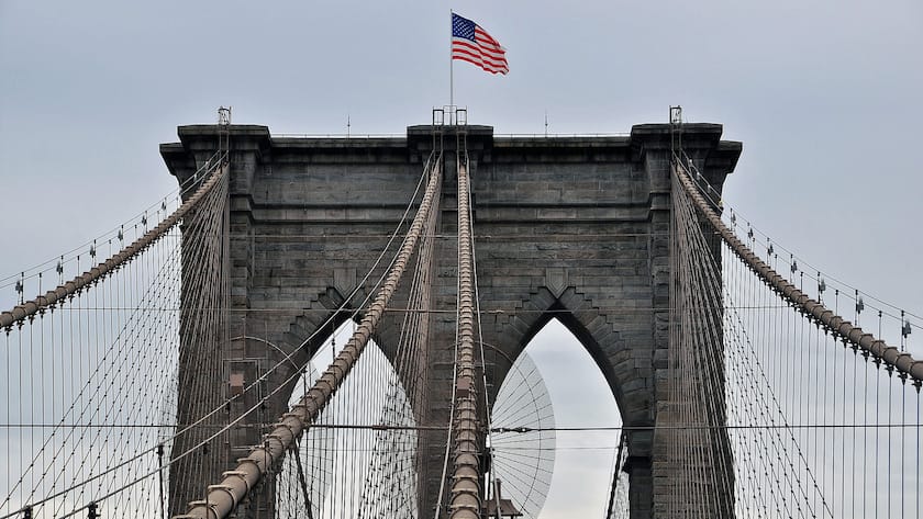 Die amerikanische Flagge weht über einem der Pfeiler der New Yorker Brooklyn Bridge.