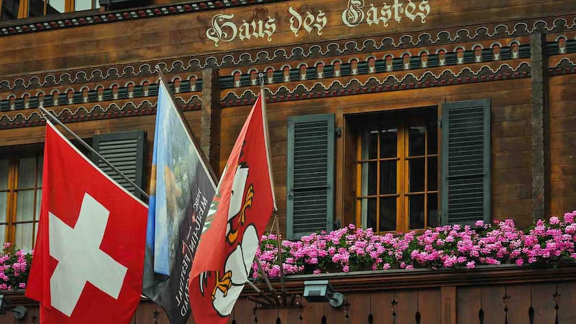 Flaggenschmuck an einem chaletartigen Gebäude im Tourismusort Gstaad.